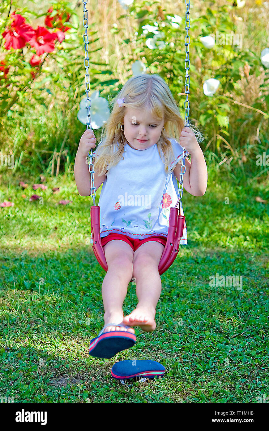 Bimba bionda su swing con flip-flop. Foto Stock