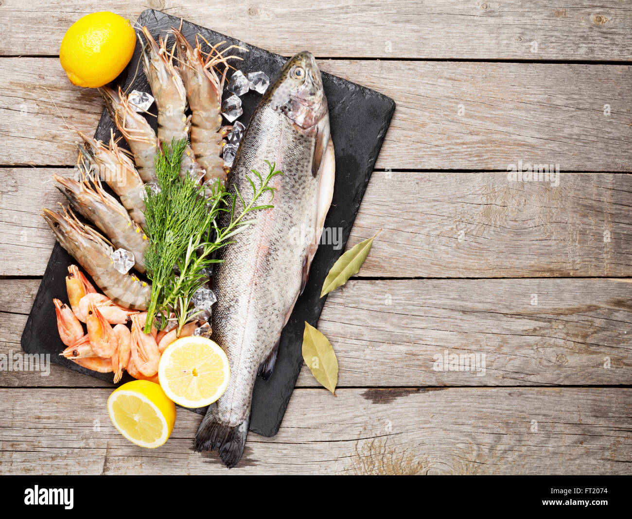 Crudo fresco il cibo del mare con spezie sulla lastra di pietra su un tavolo di legno dello sfondo. Vista superiore Foto Stock
