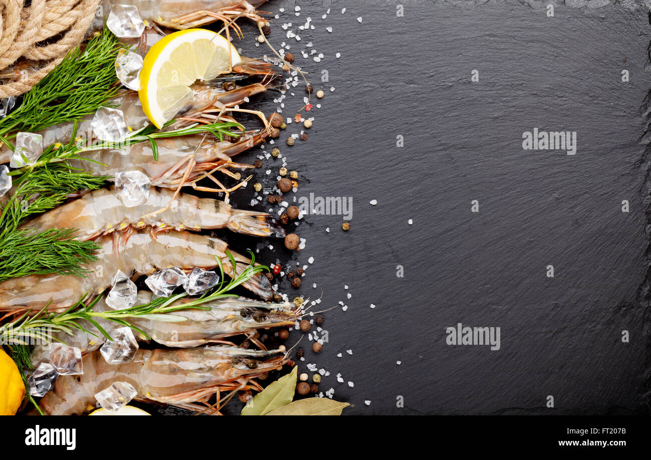 Gamberetti freschi con spezie sulla pietra nera dello sfondo. Vista da sopra con lo spazio di copia Foto Stock