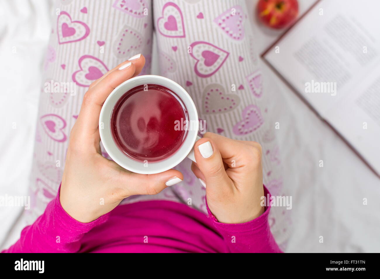 Donna con una tazza di tè di frutta a letto Foto Stock