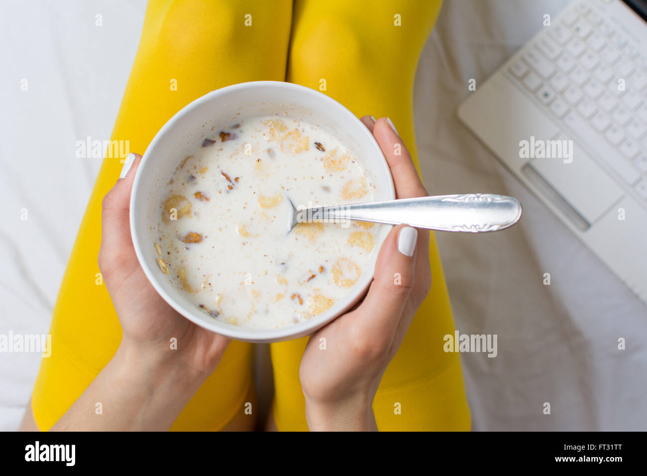 Ragazza mangiare cereali nel letto di indossare calze di colore giallo Foto Stock