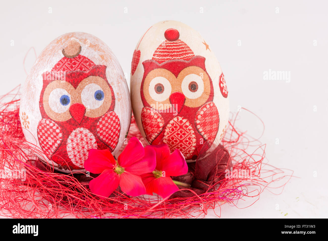 Paio di decoupage decorato uovo di Pasqua sulla paglia rosso Foto Stock