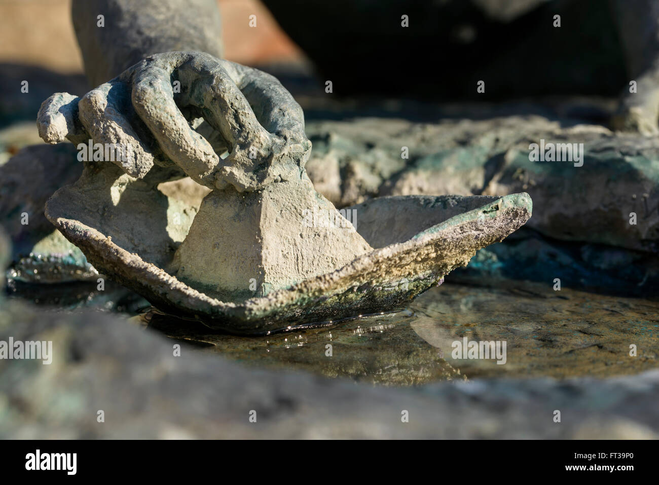 Dettaglio di una statua in bronzo della mano di un bambino che gioca con una barca di carta Foto Stock