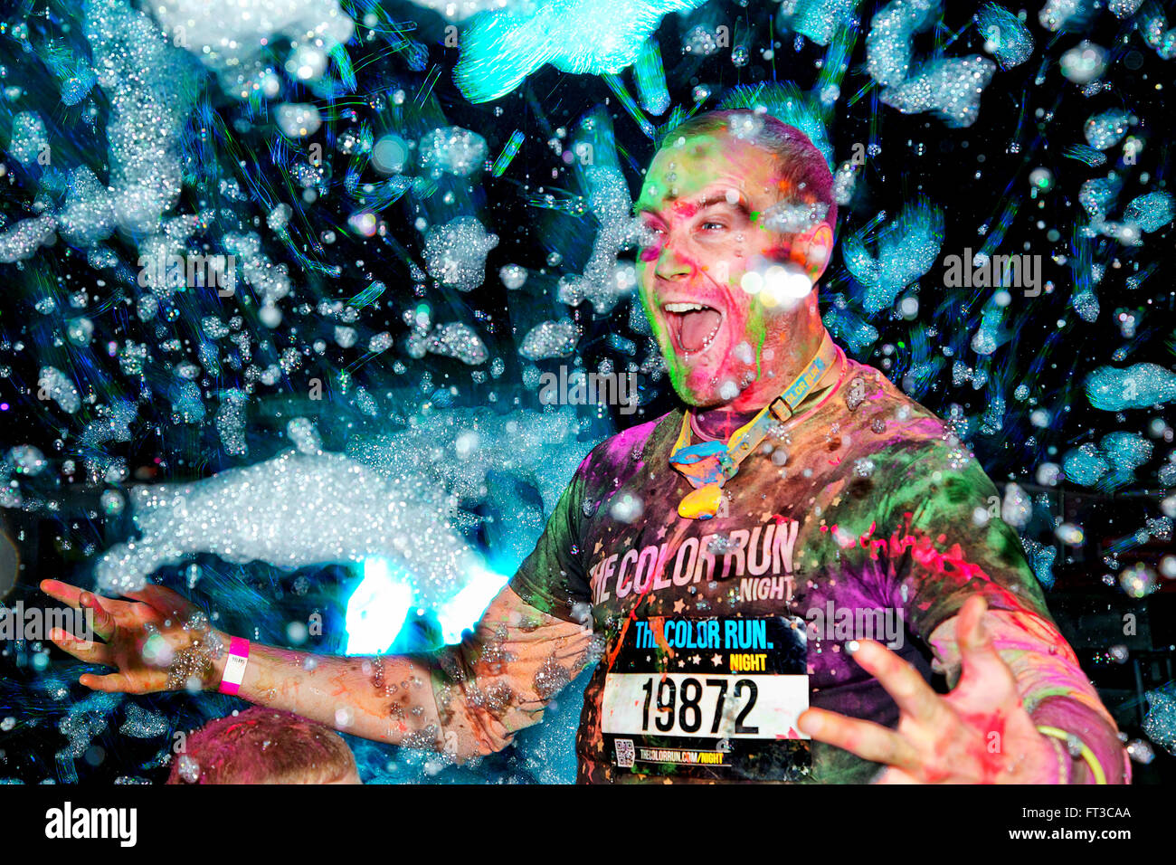 Un uomo passa attraverso un mare di bolle come egli compete nel 'Colour Run notte' fun run. Foto Stock