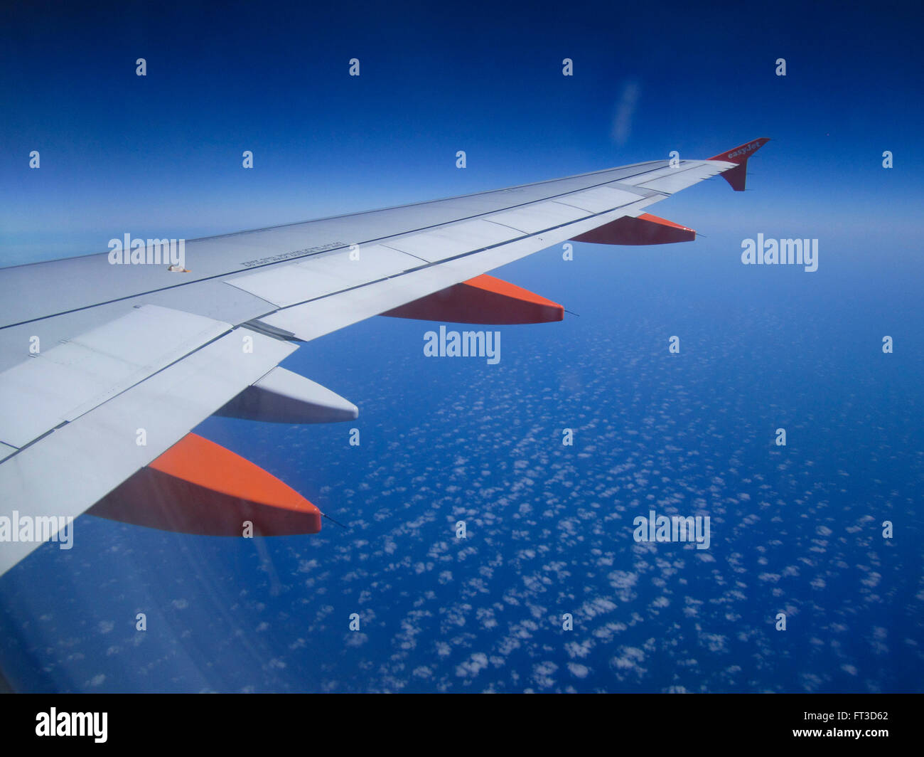 La vista dalla finestra di un aereo o un aereo di linea shwoing l'ala dell'aereo jet e un profondo cielo blu. Foto Stock