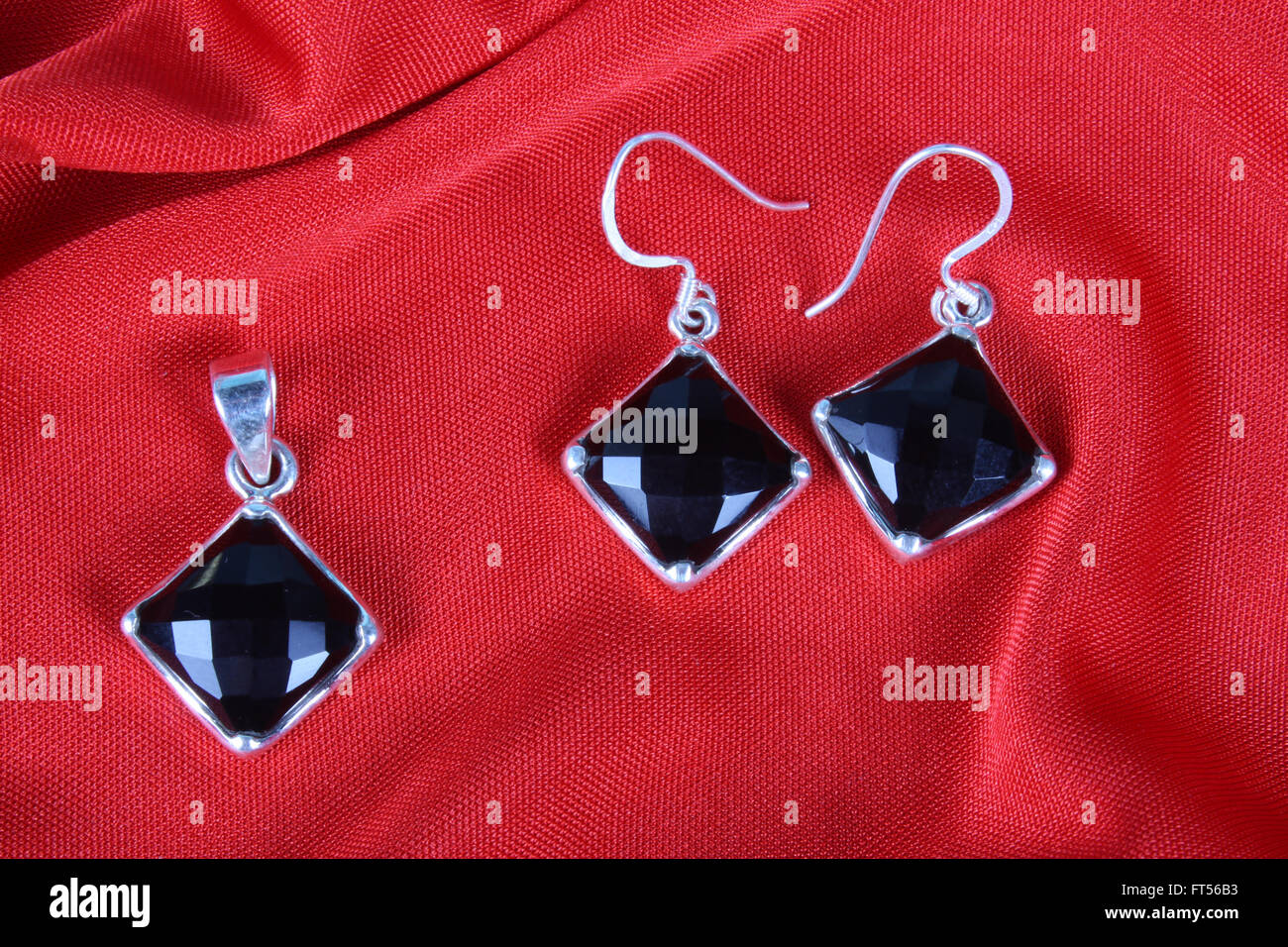 Un set di nero onyx gioielli realizzati in argento costituito da un telecomando e un paio di orecchini, sul tessuto rosso. Foto Stock