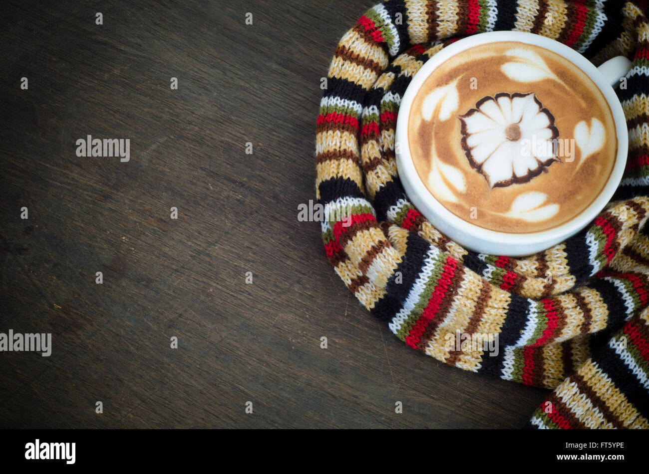 Tazza di caffè circondato la calda sciarpa su sfondo di legno Foto Stock