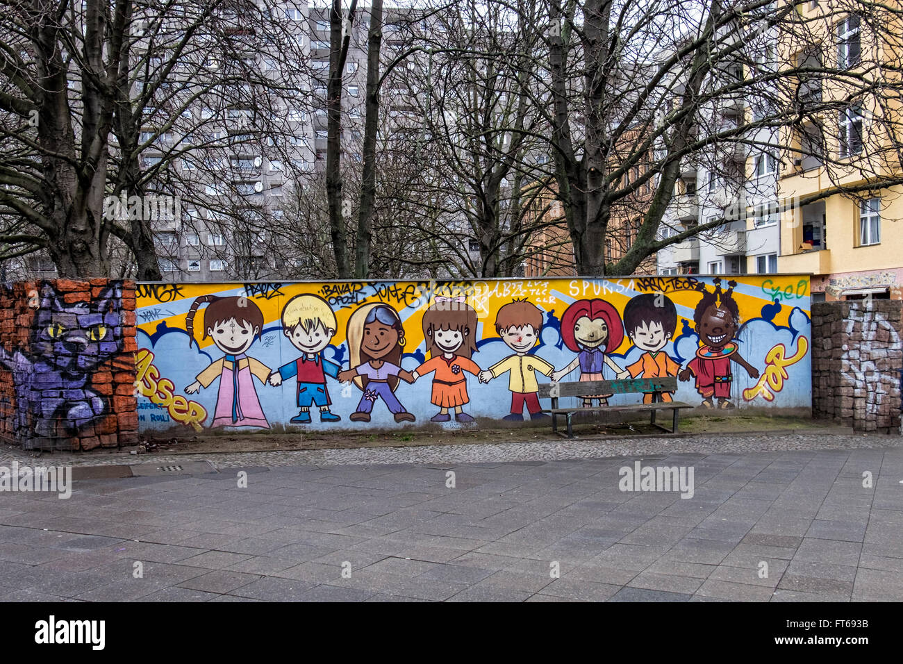 I bambini di diverse gare tenendo le mani in una colorata arte di strada lavorare sulla parete di parcheggio nel vicino Kotbusser Tor, Berlino Foto Stock