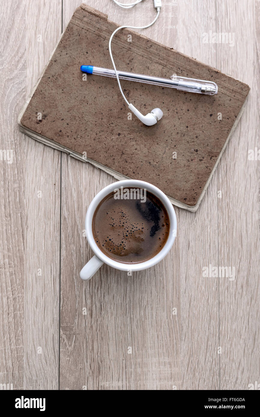 Caffè, notepad, auricolari e matita, sulla scrivania in ufficio. Foto Stock