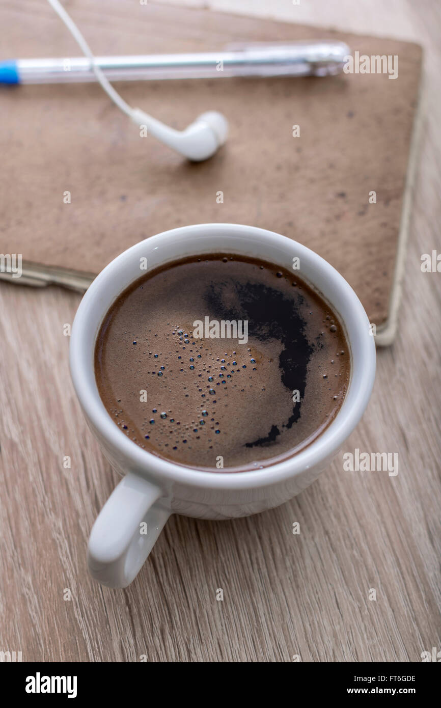 Caffè, notepad, auricolari e matita, sulla scrivania in ufficio. Foto Stock