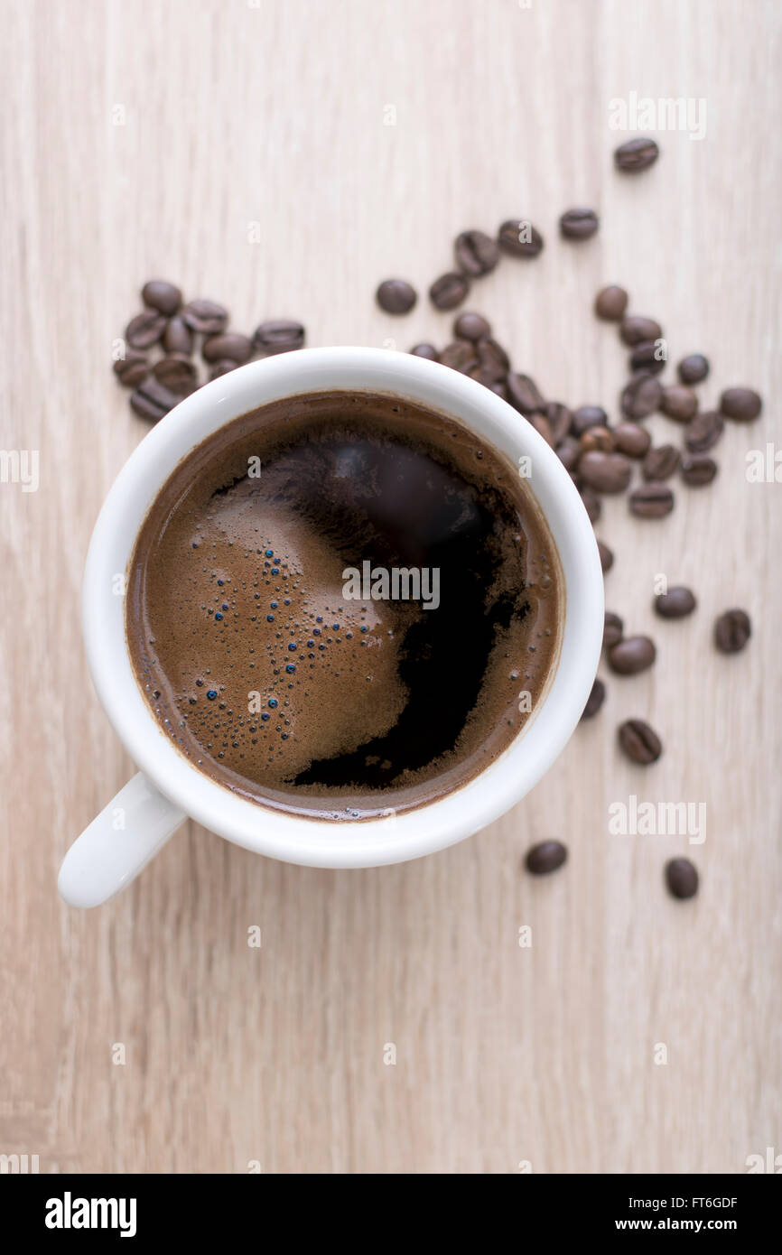 Tazza di caffè con caffè torrefatto in grani su sfondo di legno. Vista da sopra Foto Stock