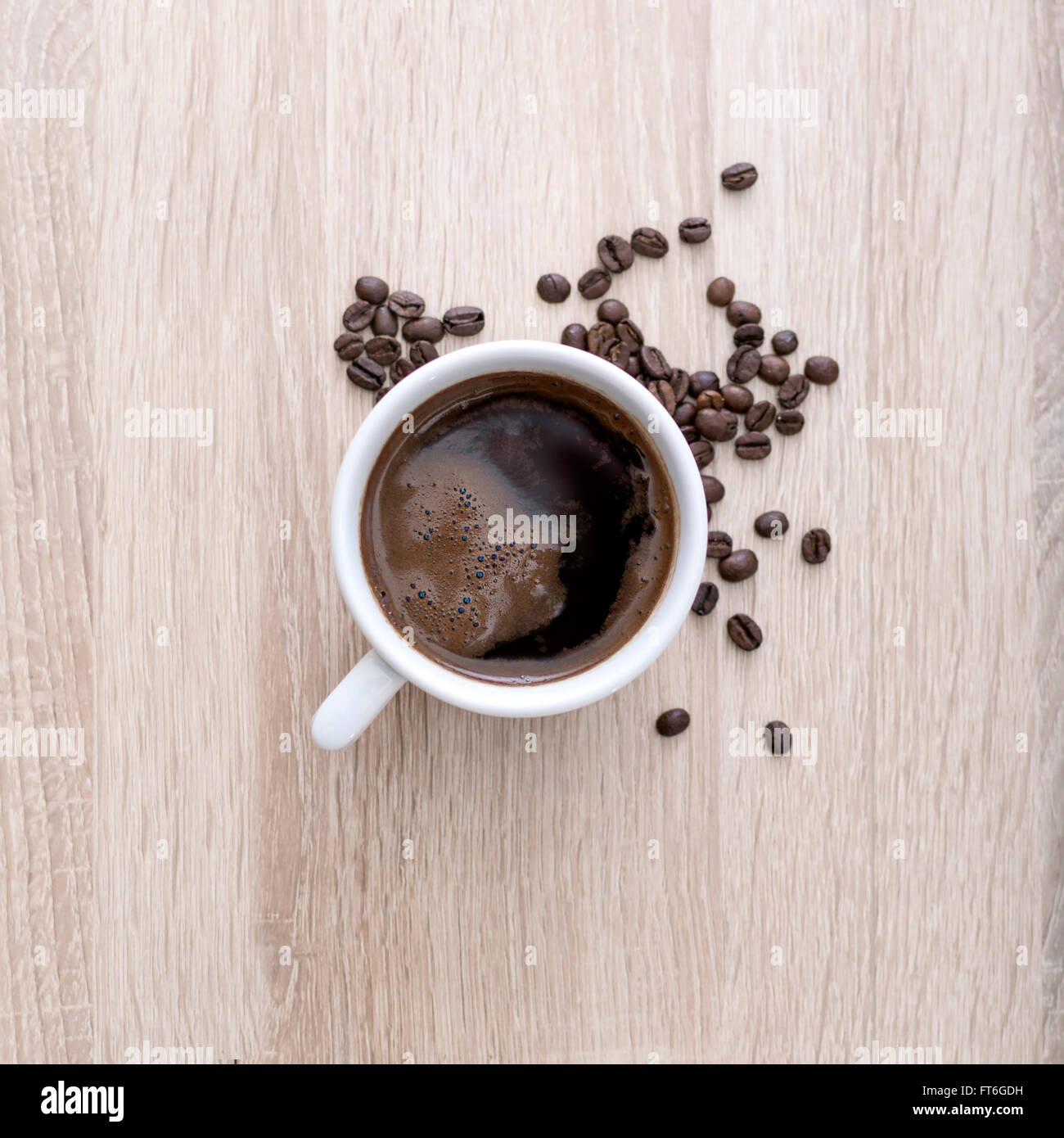 Tazza di caffè con caffè torrefatto in grani su sfondo di legno. Vista dalla parte superiore Foto Stock