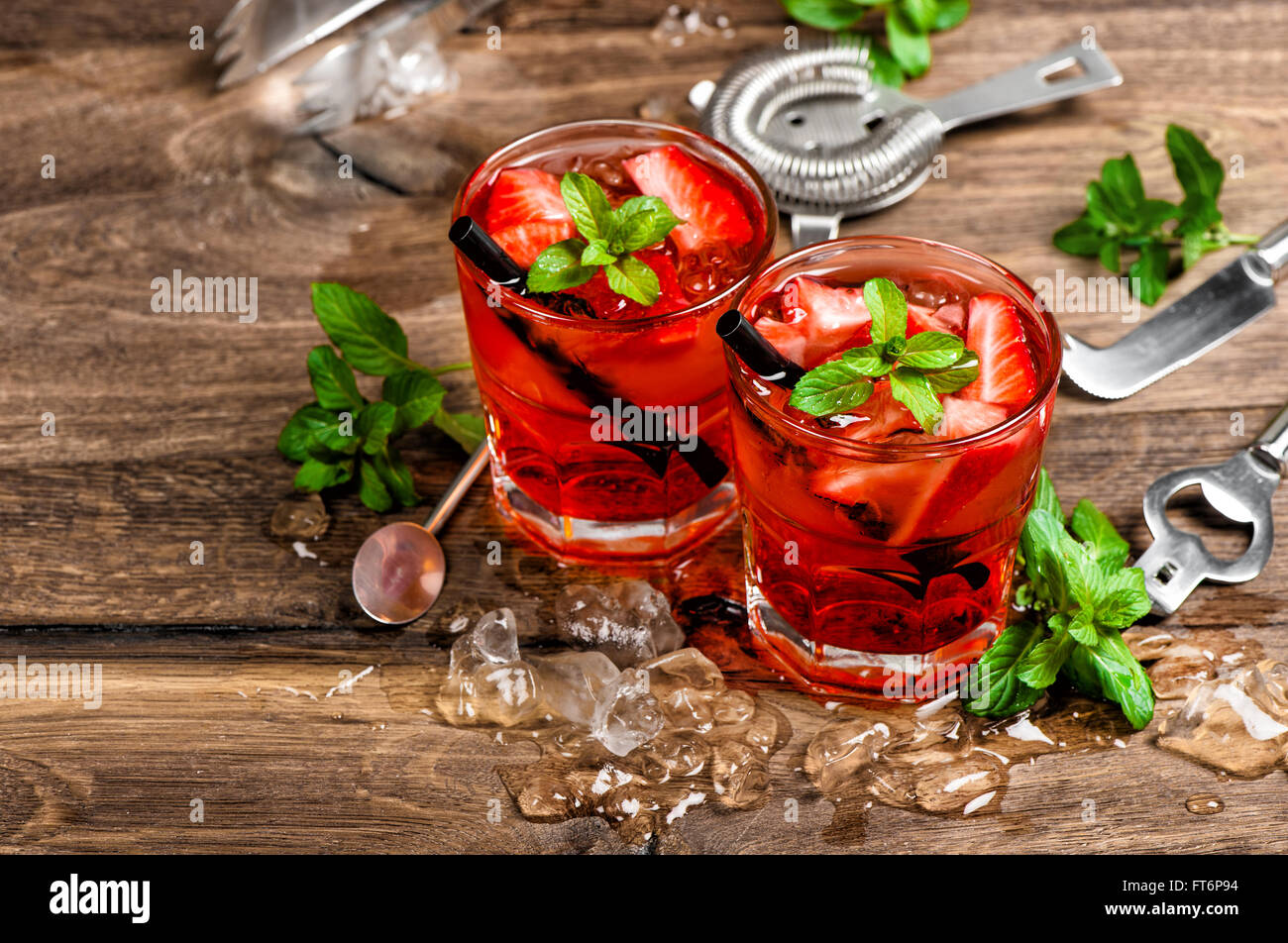Red drink con ghiaccio, foglie di menta e fragola. Cocktail rendendo gli strumenti della barra Foto Stock