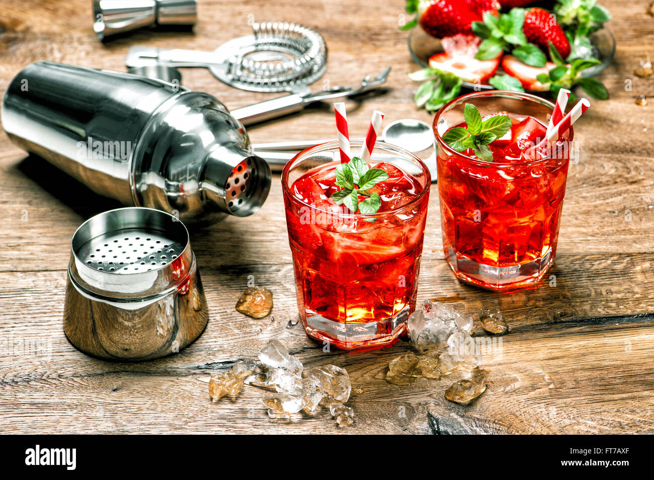 Bicchiere di bibita rosso con ghiaccio. Cocktail bar rendendo gli strumenti di legno sul tavolo da cucina Foto Stock