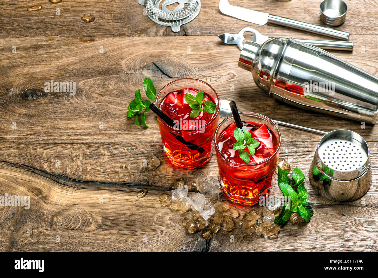 Red cocktail con ghiaccio, foglie di menta e fragola. Campari, aperol, caipirinha, mojito, soda water drink Foto Stock