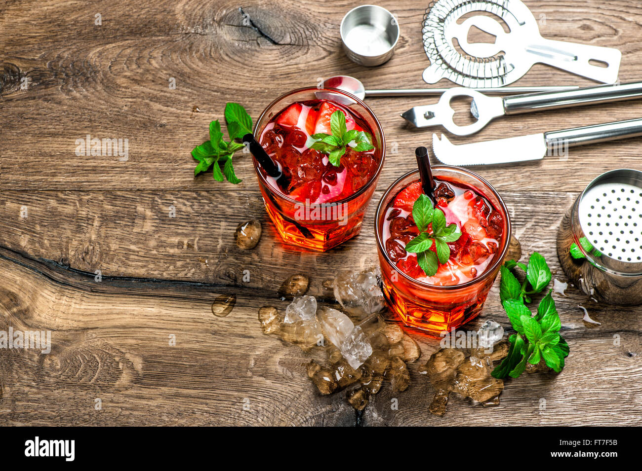 Red drink con ghiaccio, foglie di menta e fragola. Cocktail rendendo gli strumenti della barra Foto Stock