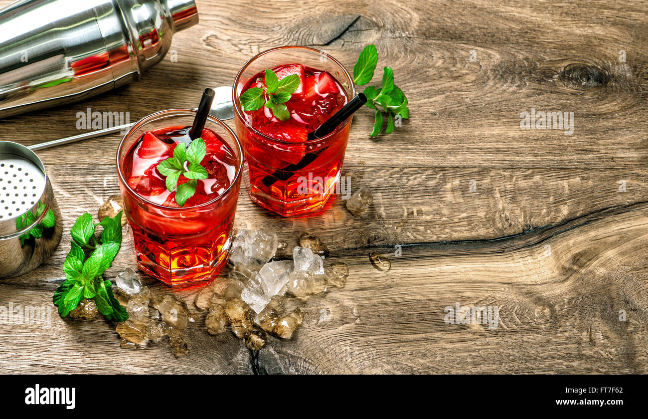 Red cocktail con ghiaccio, foglie di menta e fragola su sfondo di legno Foto Stock