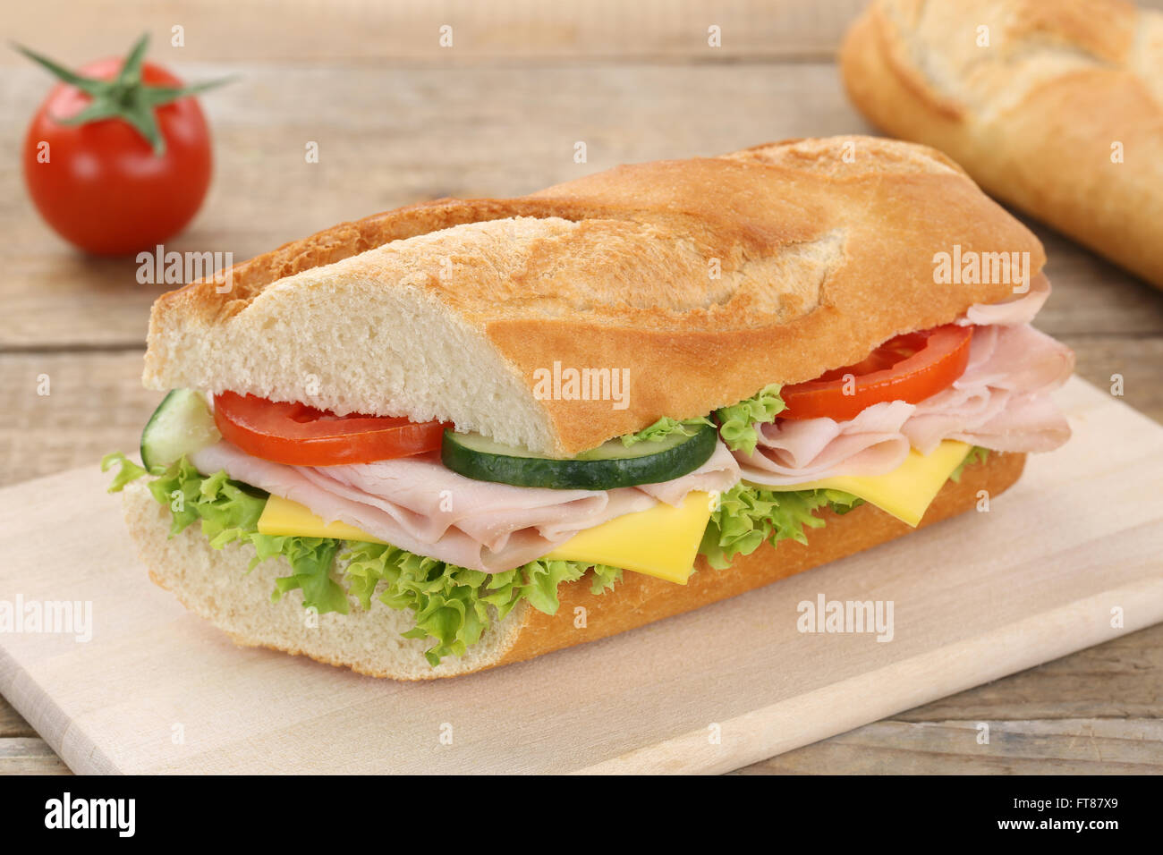 Sub baguette sandwich con prosciutto e formaggio, pomodori e lattuga per la prima colazione Foto Stock