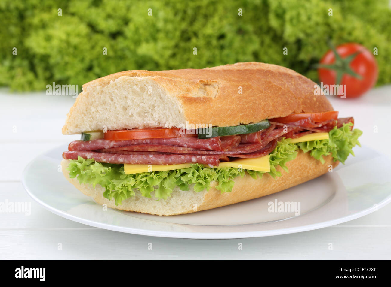 Sub baguette sandwich sulla piastra con salame prosciutto, formaggio, pomodori e lattuga per la prima colazione Foto Stock