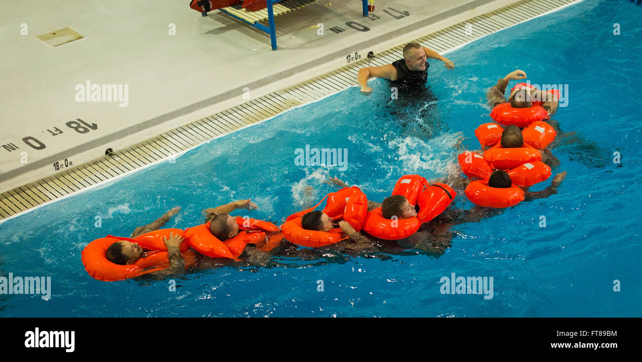 Il CBP Ufficio di aria e i piloti marittimi sono sottoposti a formazione di acqua che simula un crash in acque aperte e in modo sicuro il uscire dall'aereo e a bordo di una zattera come gruppo presso il National Air Training Center nella città di Oklahoma, Oklahoma. Un istruttore sovrintende una "linea conga" dove gli studenti possono assemblare come un team e manovrare come un gruppo di una zattera di salvataggio. Foto di, James Tourtellotte. Foto Stock