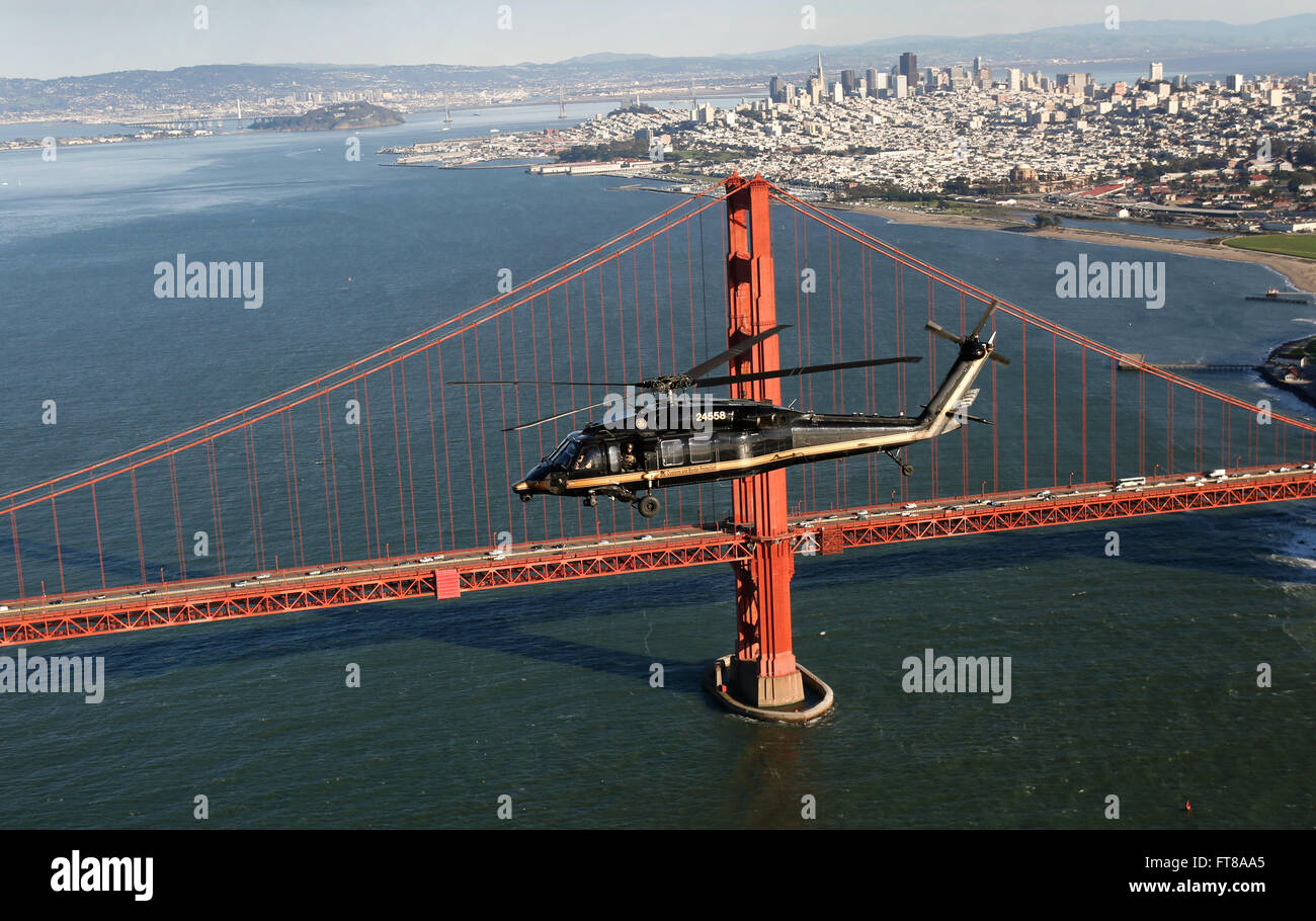 Un elicottero della dogana e della protezione dei confini degli Stati Uniti Black Hawk vola sul Golden Gate Bridge di San Francisco con lo skyline della città visibile sullo sfondo. Questa foto è stata scattata il 1 febbraio 2016, durante le operazioni del Super Bowl 50. Foto Stock