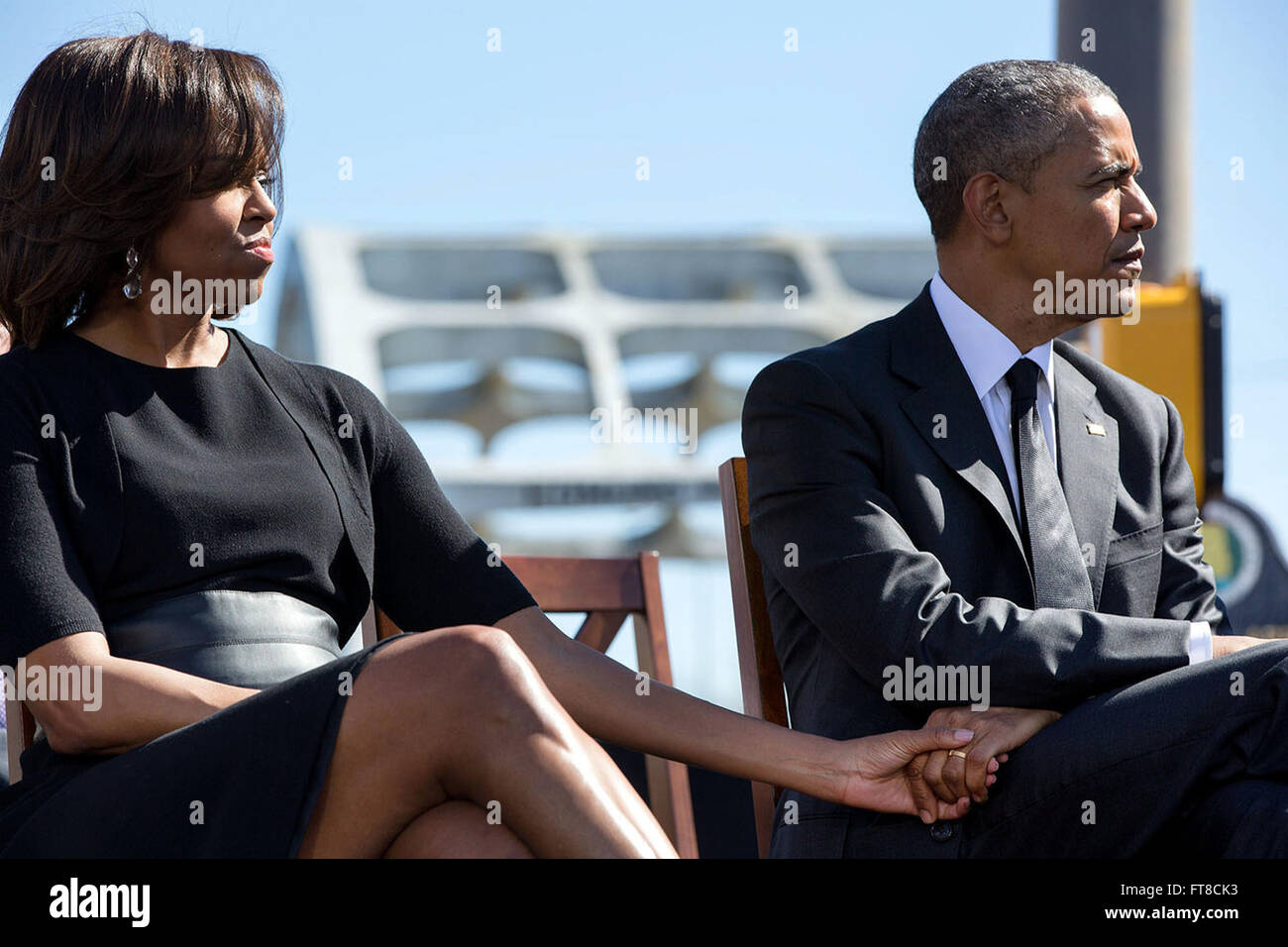 Questa immagine cattura un momento durante il 50 ° anniversario di Bloody Sunday e la marcia da Selma a Montgomery, mostrando il presidente Obama e la First Lady Michelle Obama che si tengono per mano mentre ascoltano il Rep. John Lewis. Il momento era fugace, quando presto cominciarono ad applaudire. Foto Stock