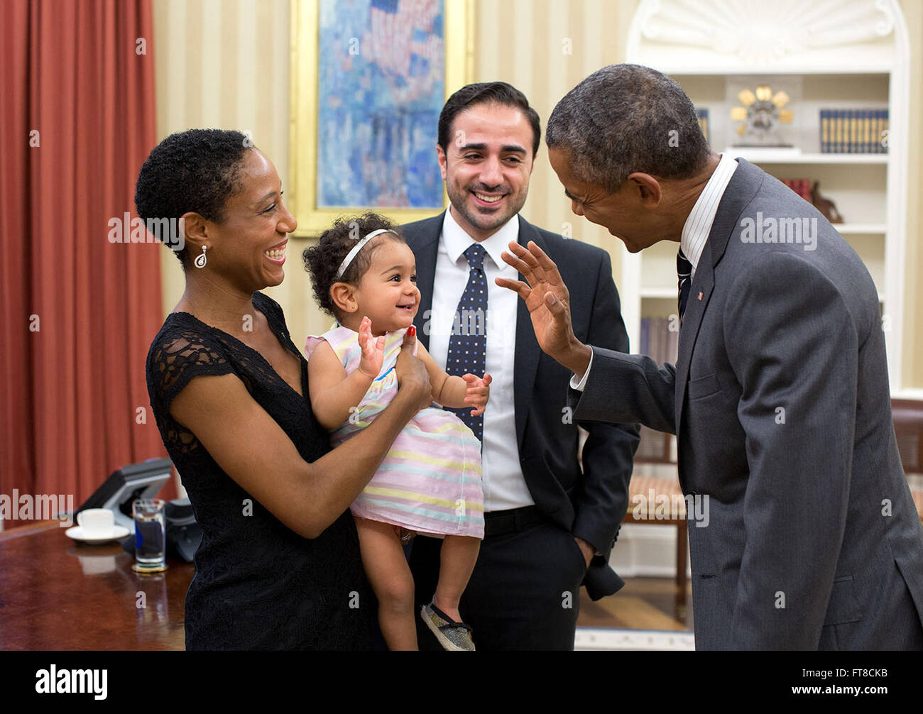 Questa fotografia ufficiale, scattata nell'ufficio ovale, mostra il presidente Obama che sventolava ad Alya Dorelien Bitar, la giovane figlia di Maher Bitar, durante una foto di famiglia. L'immagine cattura un momento di diplomazia e famiglia, riflettendo il significato delle connessioni personali in contesti politici. Foto Stock