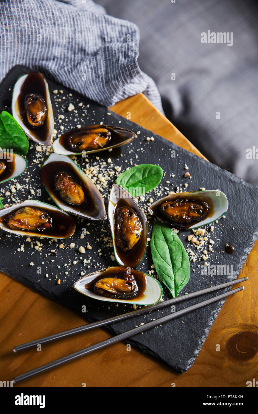 Piatto asiatico - le cozze in sticky salsa dolce, con arachidi e spinaci Foto Stock