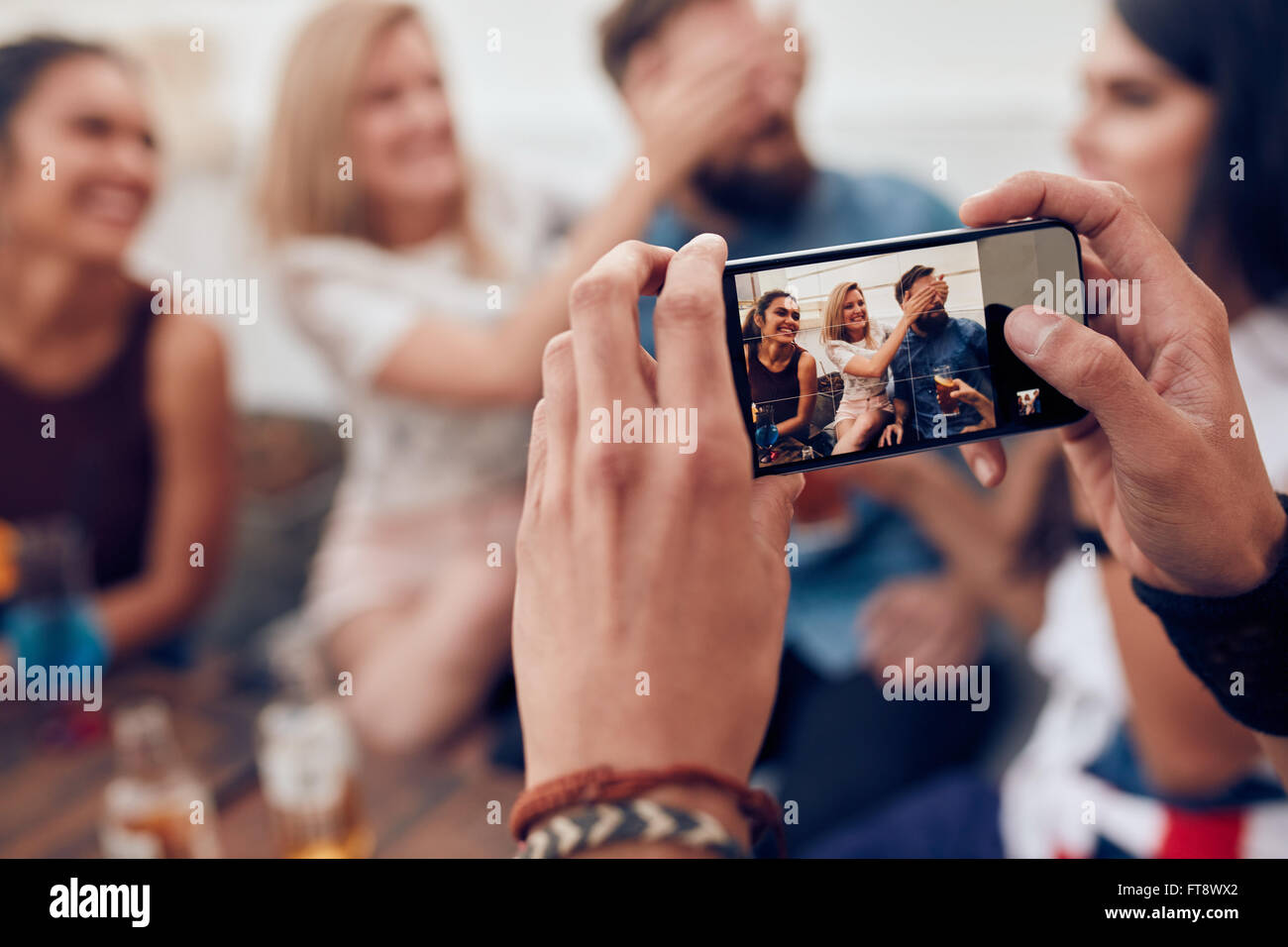 Fotografare un gruppo di amici con il telefono cellulare. I giovani divertirsi a una festa. Foto Stock