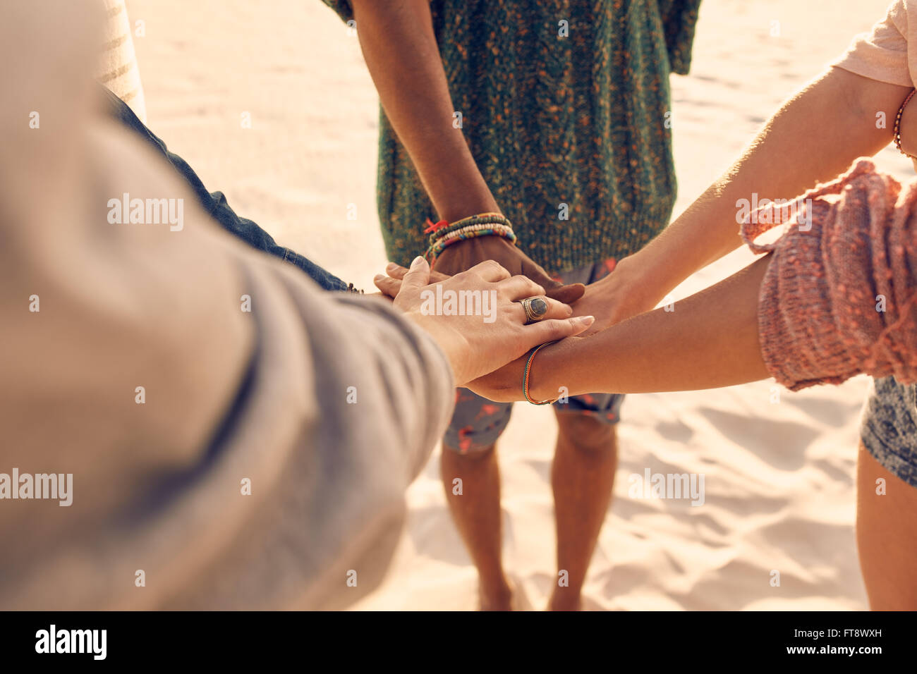 Gli amici presso la spiaggia di mettere le mani insieme. Gruppo multirazziale di giovani con le mani nella pila in spiaggia. Foto Stock