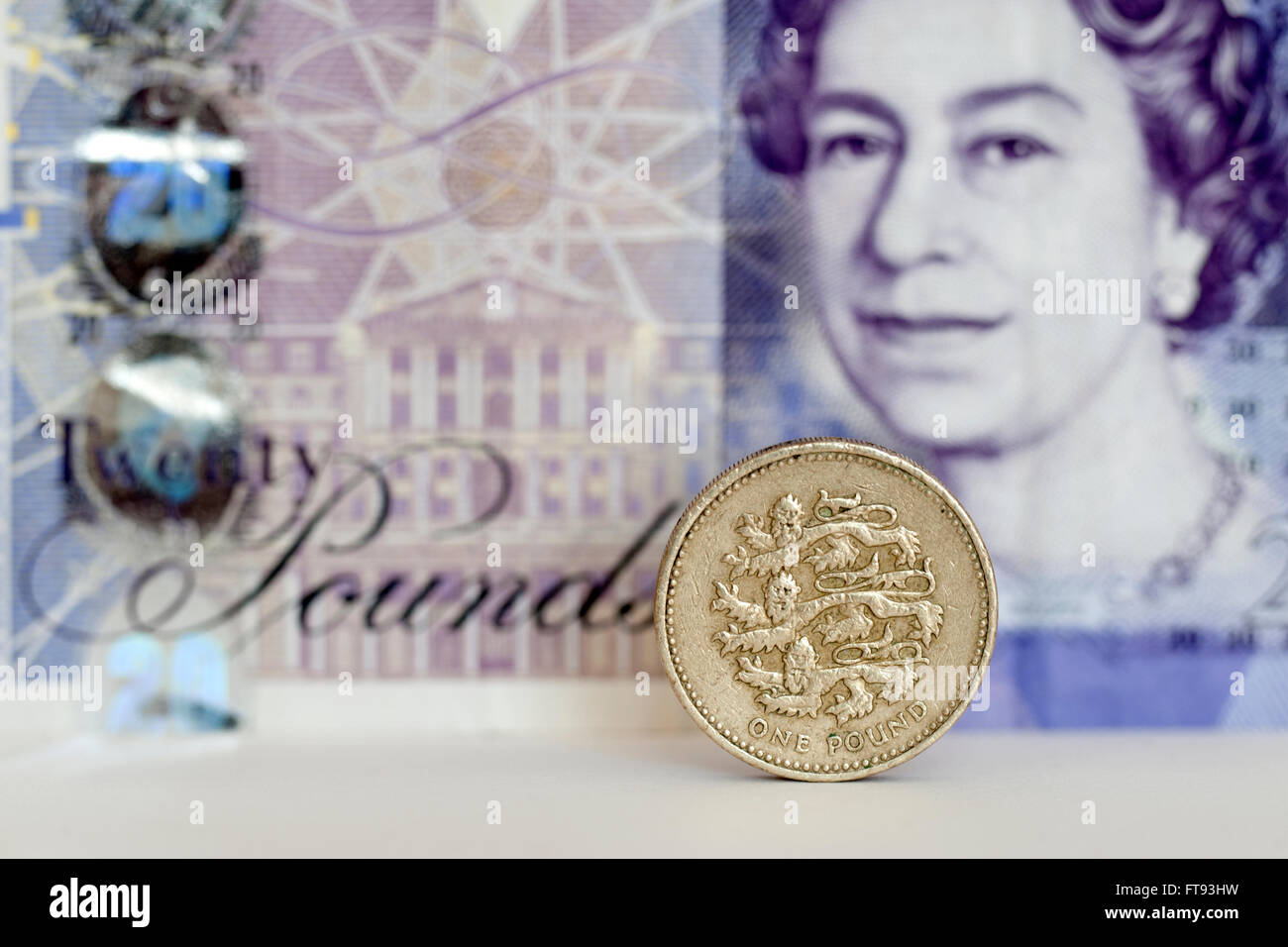 Una sterlina moneta con venti libbre banconota dietro Foto Stock