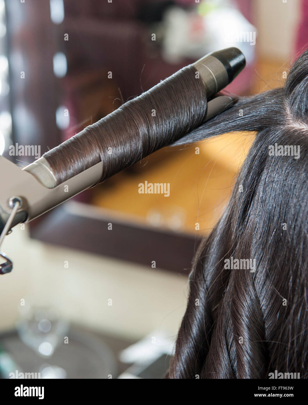 Primo piano dettaglio femminile di womens fissanti per capelli stile essendo al salone di parrucchiere Foto Stock