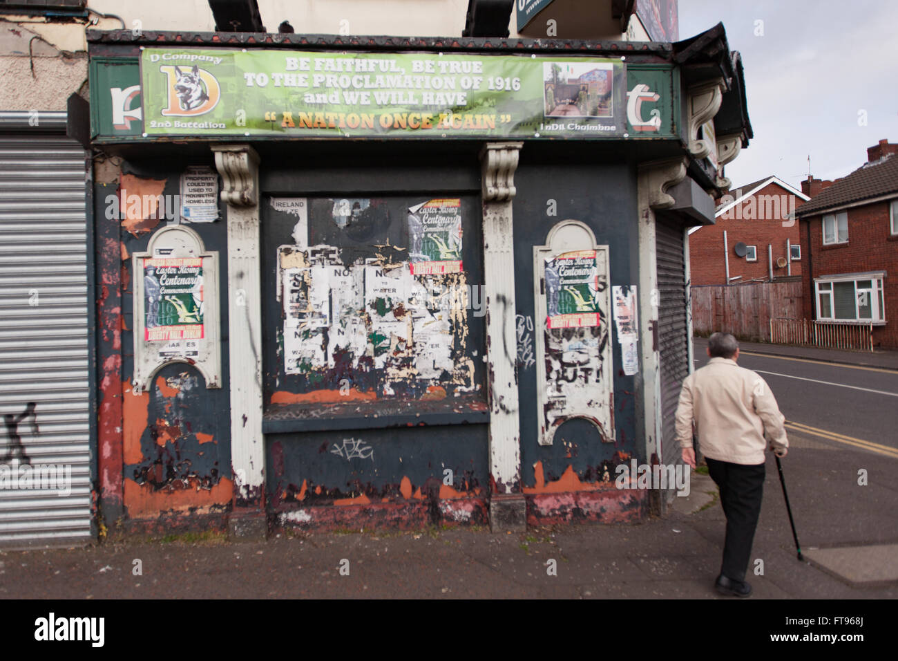 Parte occidentale di Belfast, Irlanda. 25 marzo, 2016. Un uomo cammina passati in disuso pub che si chiama il ribelle di riposo i preparativi per commemorare il centenario della Pasqua rising inizia nella parte occidentale di Belfast Credit: Bonzo Alamy/Live News Foto Stock