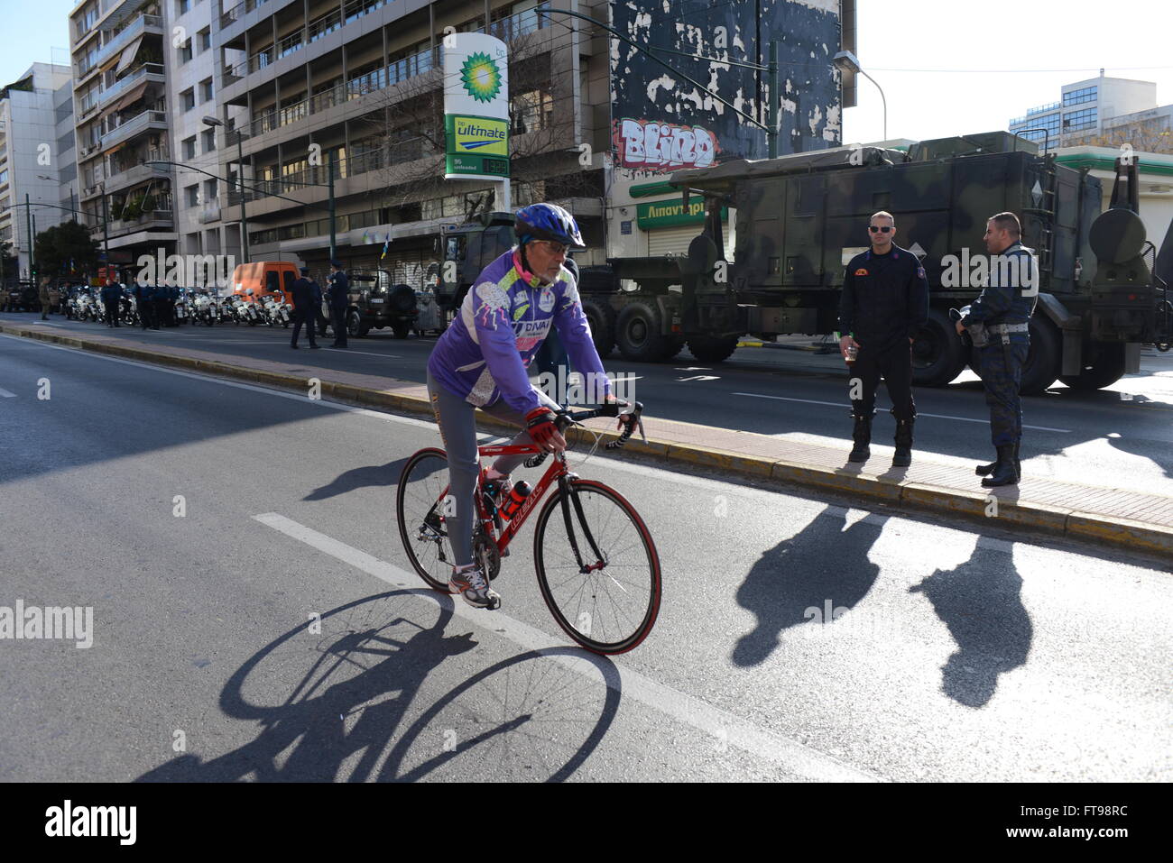 Atene, Grecia. 25 Mar, 2016. Un ciclista sta passando in Viale Syggrou in Atene, tra veicoli militari, prima dell'inizio della sfilata. Indipendenza greca il giorno che è una festa nazionale si celebra ogni anno in Grecia per commemorare l inizio della guerra di indipendenza greca nel 1821 contro l'Impero Ottomano. Nella capitale della Grecia ad Atene un enorme parata militare si svolge come omaggio per il giorno speciale. Credito: Dimitrios Karvountzis/Pacific Press/Alamy Live News Foto Stock