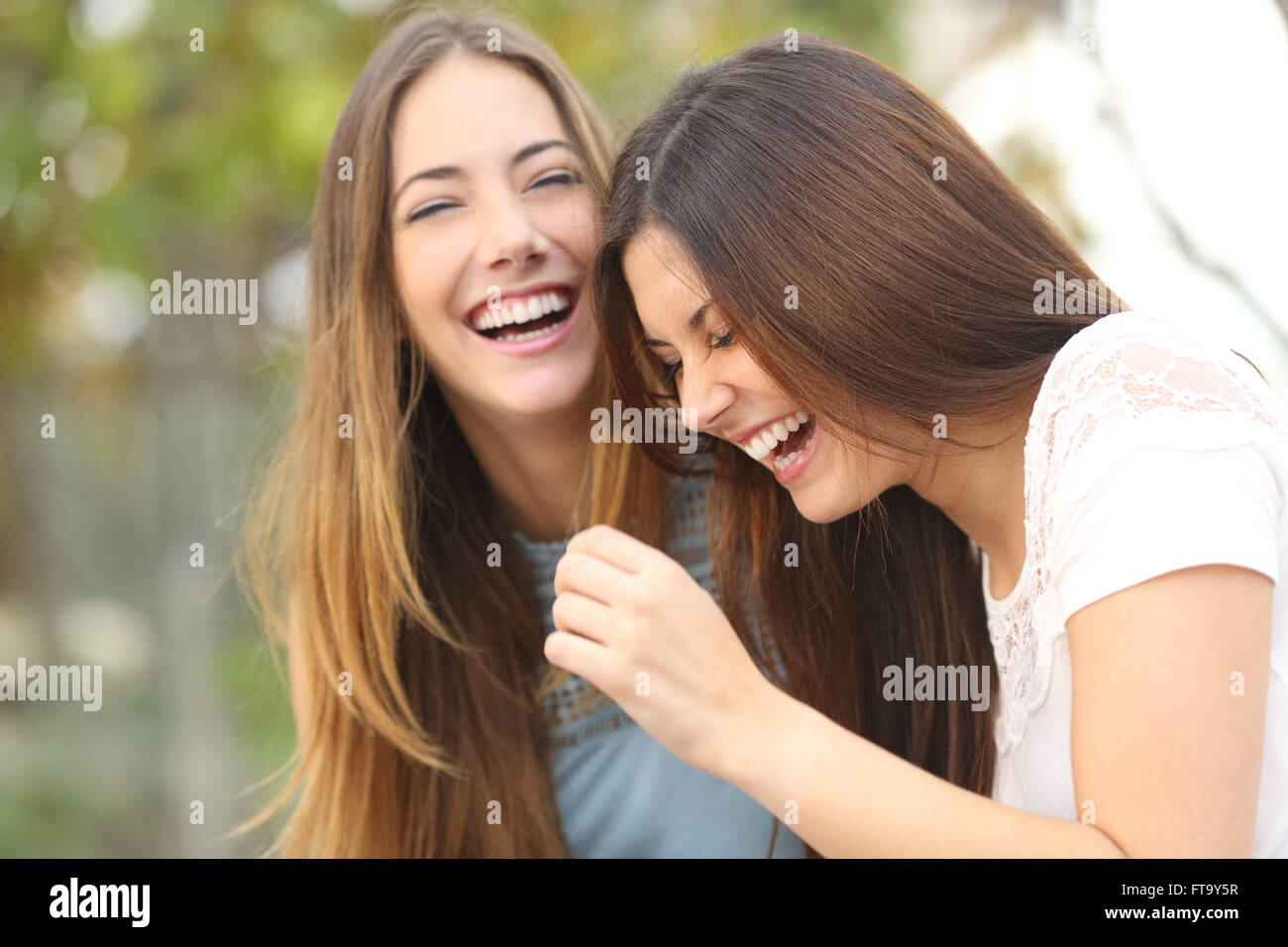 Due donna felice amici ridere insieme in un parco con uno sfondo verde Foto Stock
