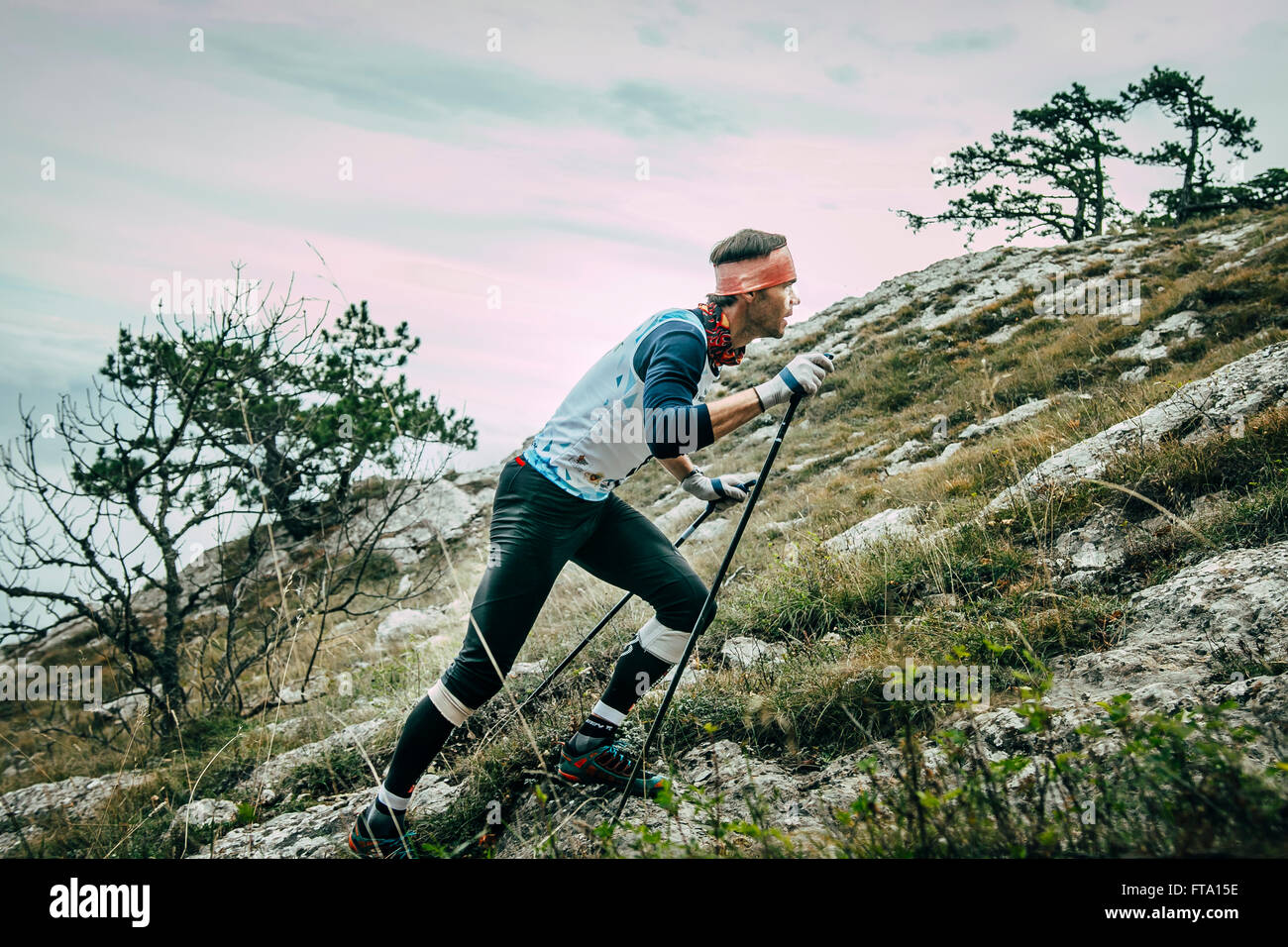 Atleta maschio si arrampica su pendio di montagna durante la maratona di montagna Foto Stock