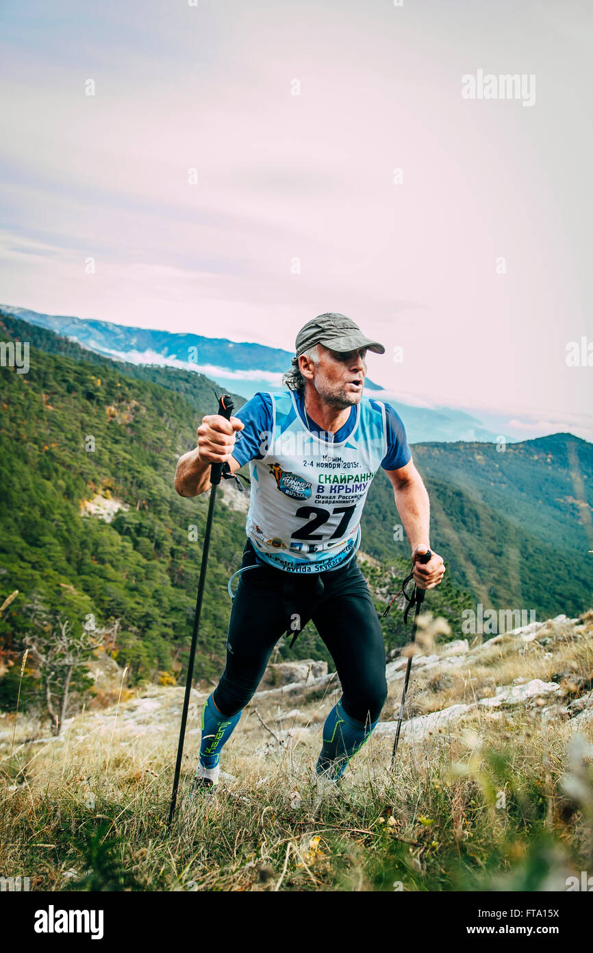 Attraente uomo di mezza età arrampicate Montagna con il nordic walking durante la maratona di montagna Foto Stock