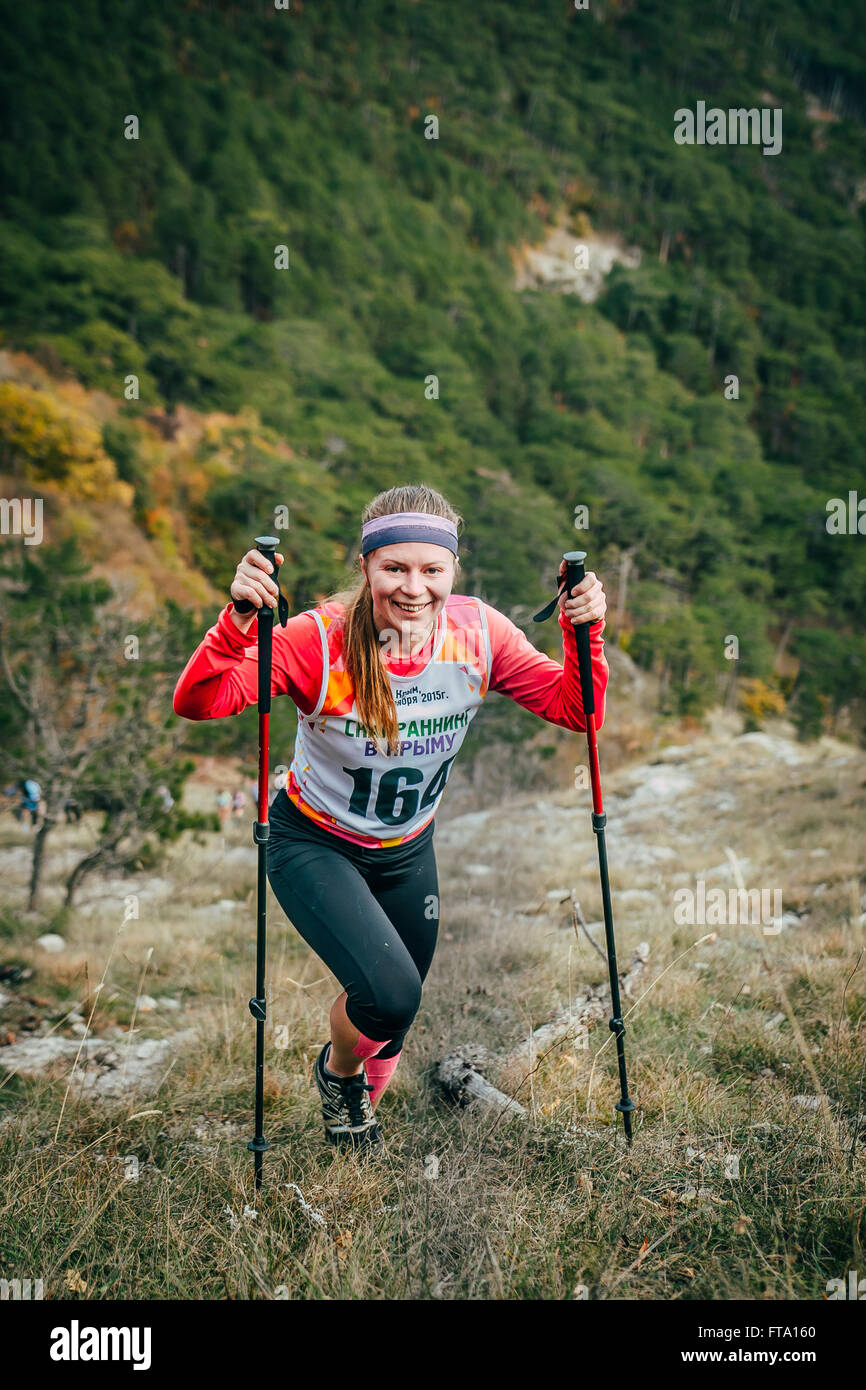 Ragazza atleta con bastoni da passeggio in salita durante la maratona di montagna Foto Stock