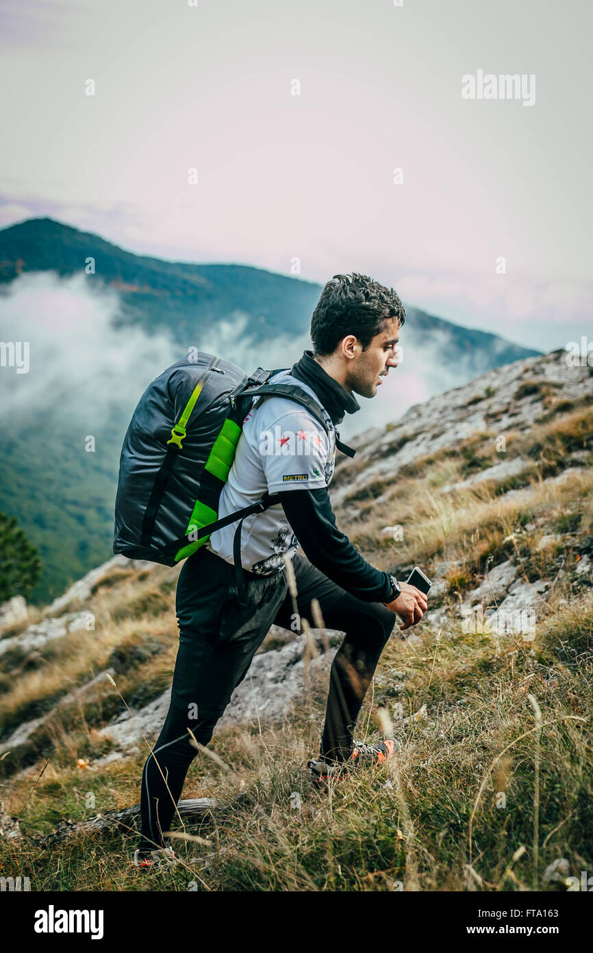 Atleta con bastoni da passeggio in salita durante la maratona di montagna Foto Stock