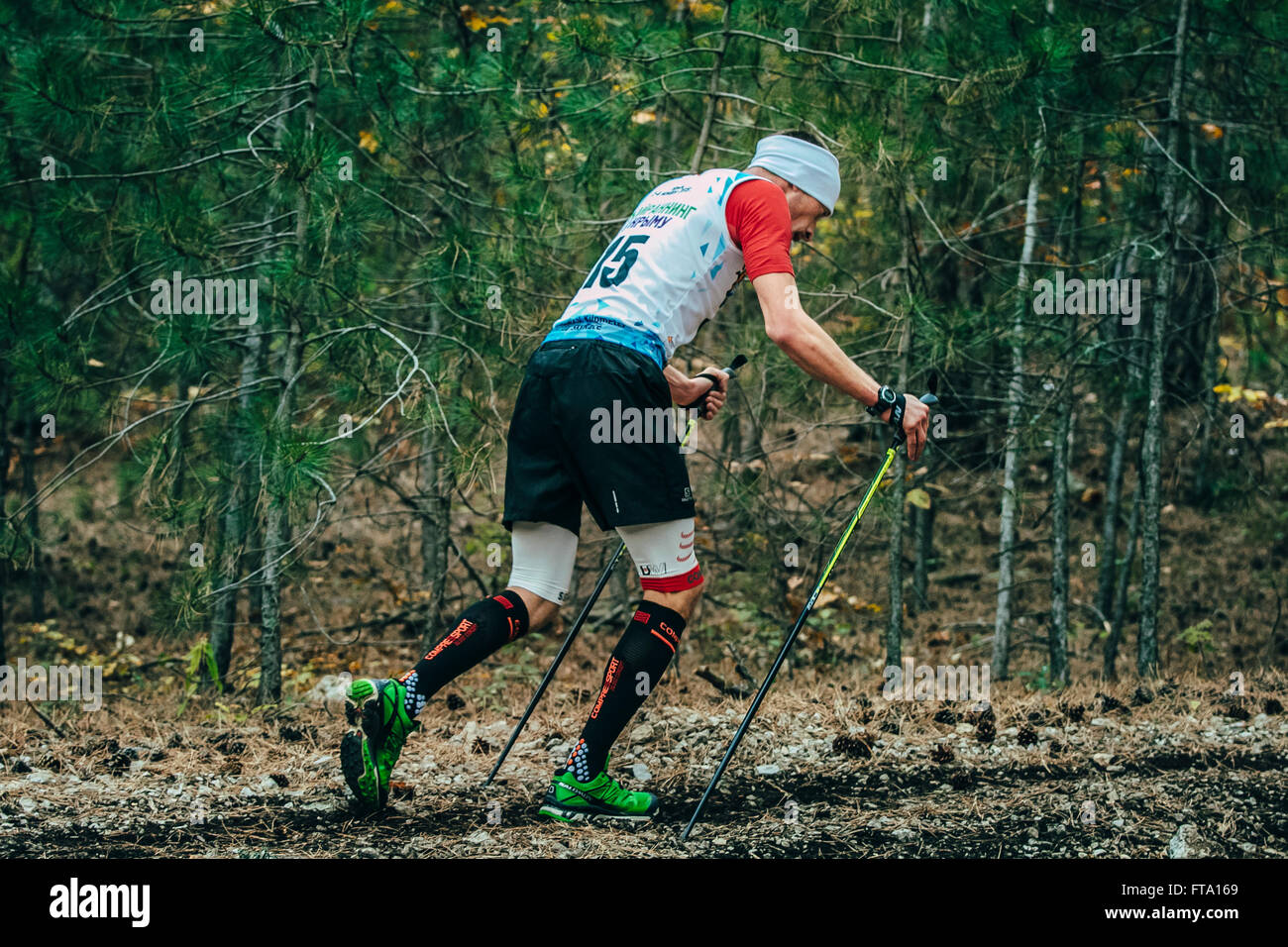 Atleta che corre con il nordic walking in calze di compressione durante la maratona di montagna Foto Stock