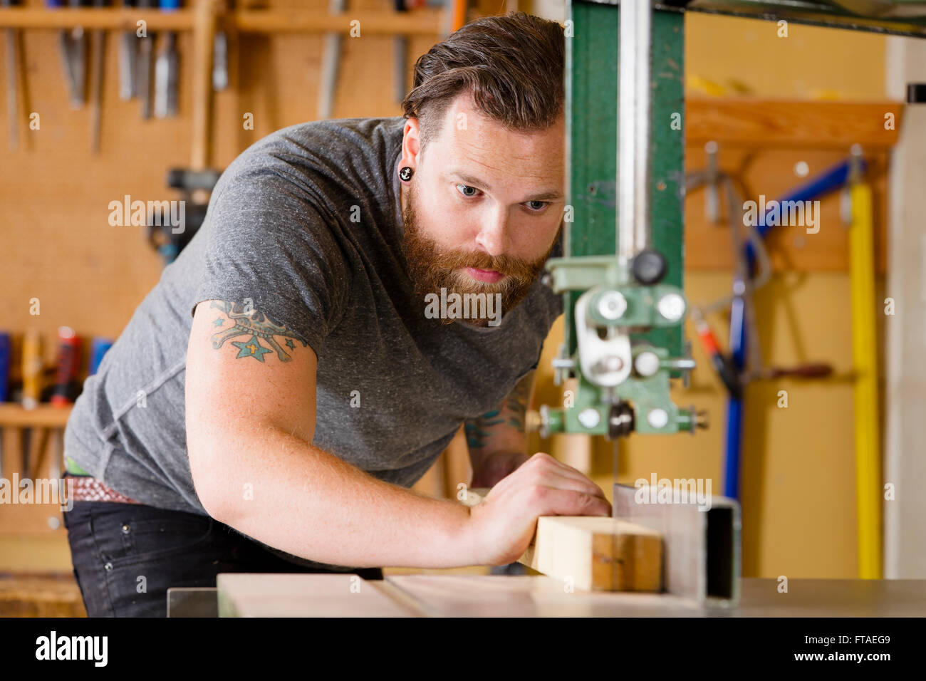 Artigiano utilizzando una sega a nastro per il legno divisione listone in officina Foto Stock