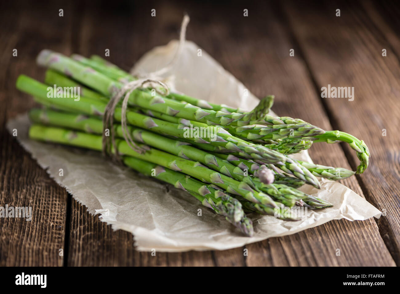 Gli asparagi verdi (freschi raccolti) su un vecchio tavolo di legno (messa a fuoco selettiva) Foto Stock