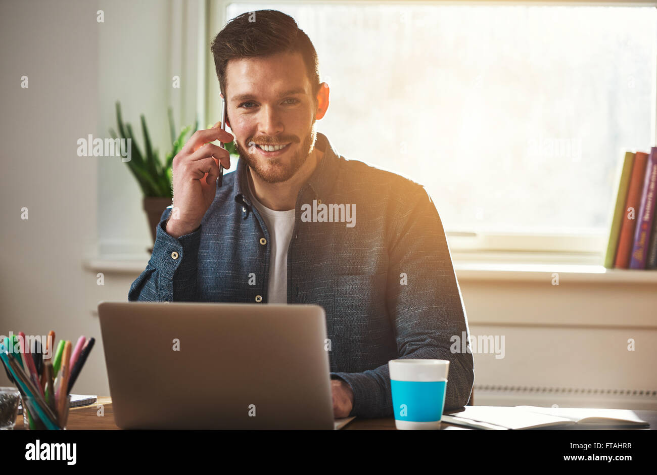 Imprenditore parlando al telefono di sorridere alla telecamera Foto Stock