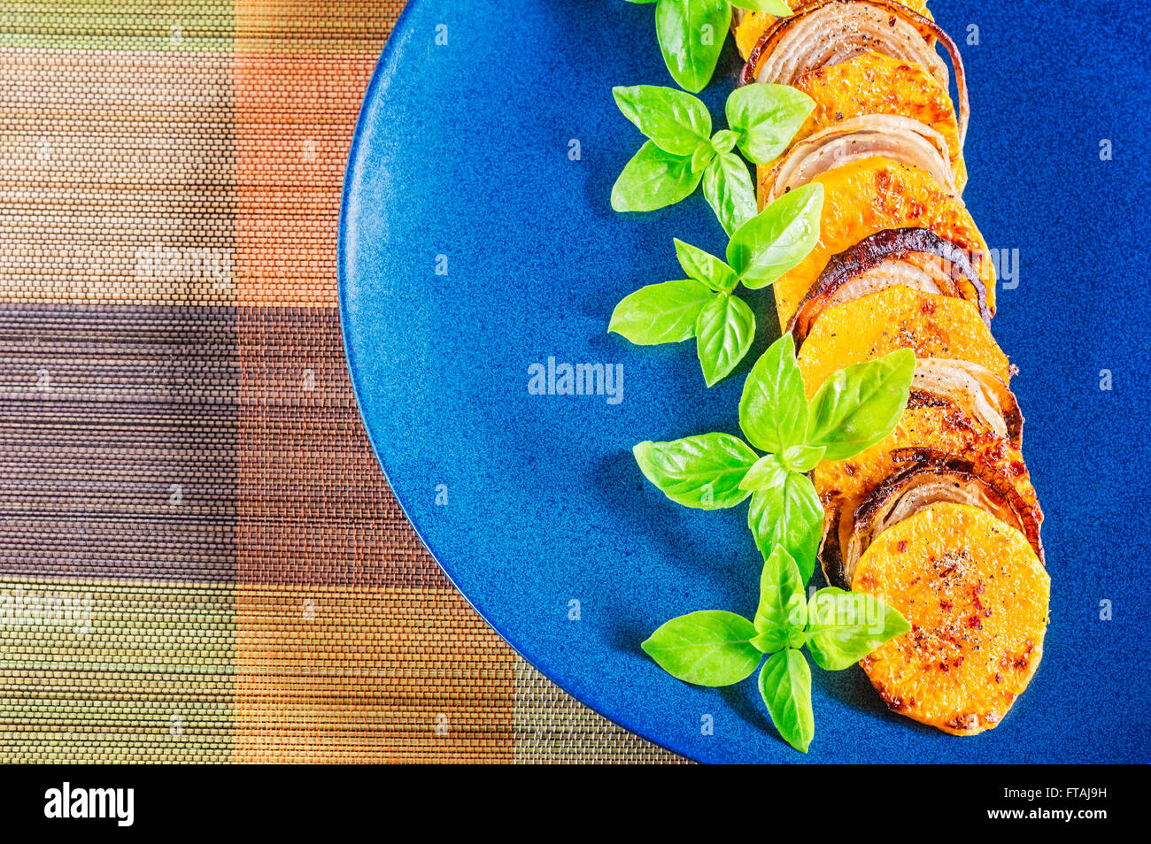 Fila di speziato arrosto di zucca e anelli di cipolla con le foglie di basilico. Foto Stock
