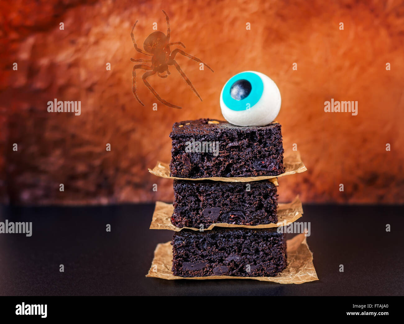 Halloween chocolate chip brownies con un occhio commestibile decorazione a sfera e una crociera silhouette su una pergamena sfondo. Foto Stock