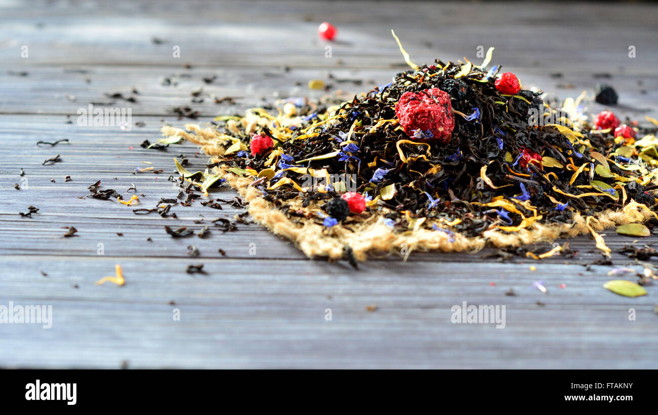 Asciugare il tè con i frutti di bosco e petali di fiori sul tavolo Foto Stock