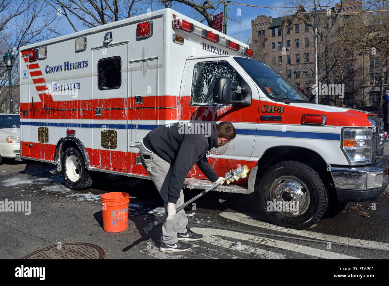 Un giovane uomo bagna un Hatzalah ambulanza sulla Eastern Parkway in Crown Heights, Brooklyn, New York City Foto Stock