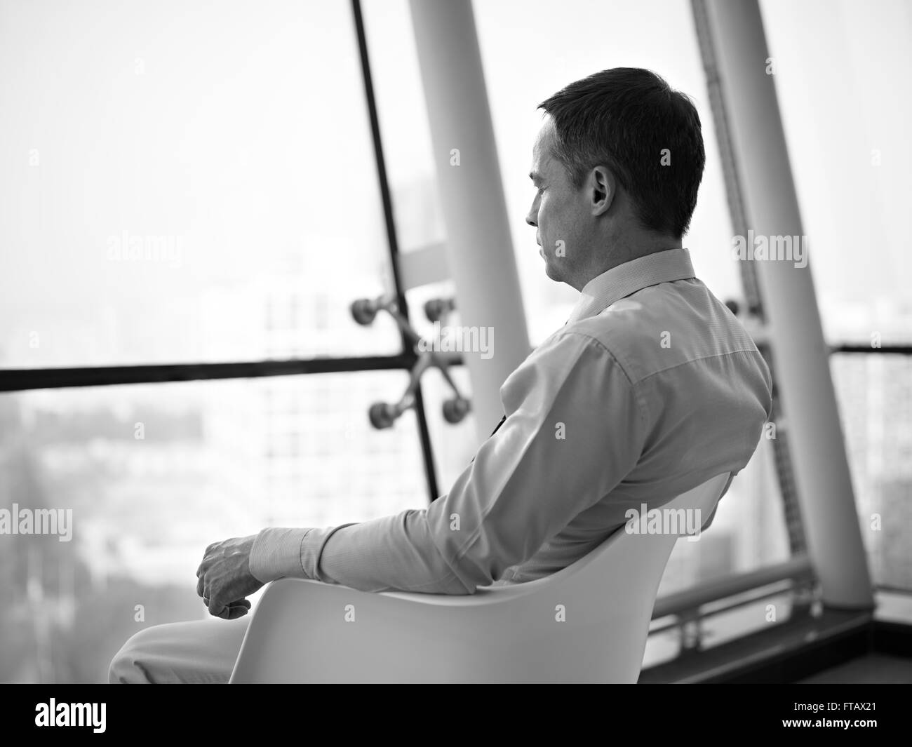 Business executive seduta dalla finestra pensando Foto Stock