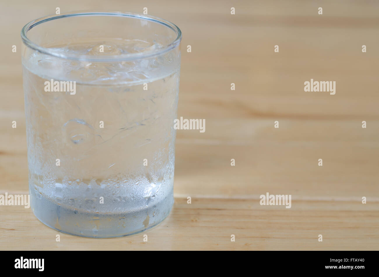 Bicchiere di acqua con ghiaccio sul tavolo di legno Foto Stock