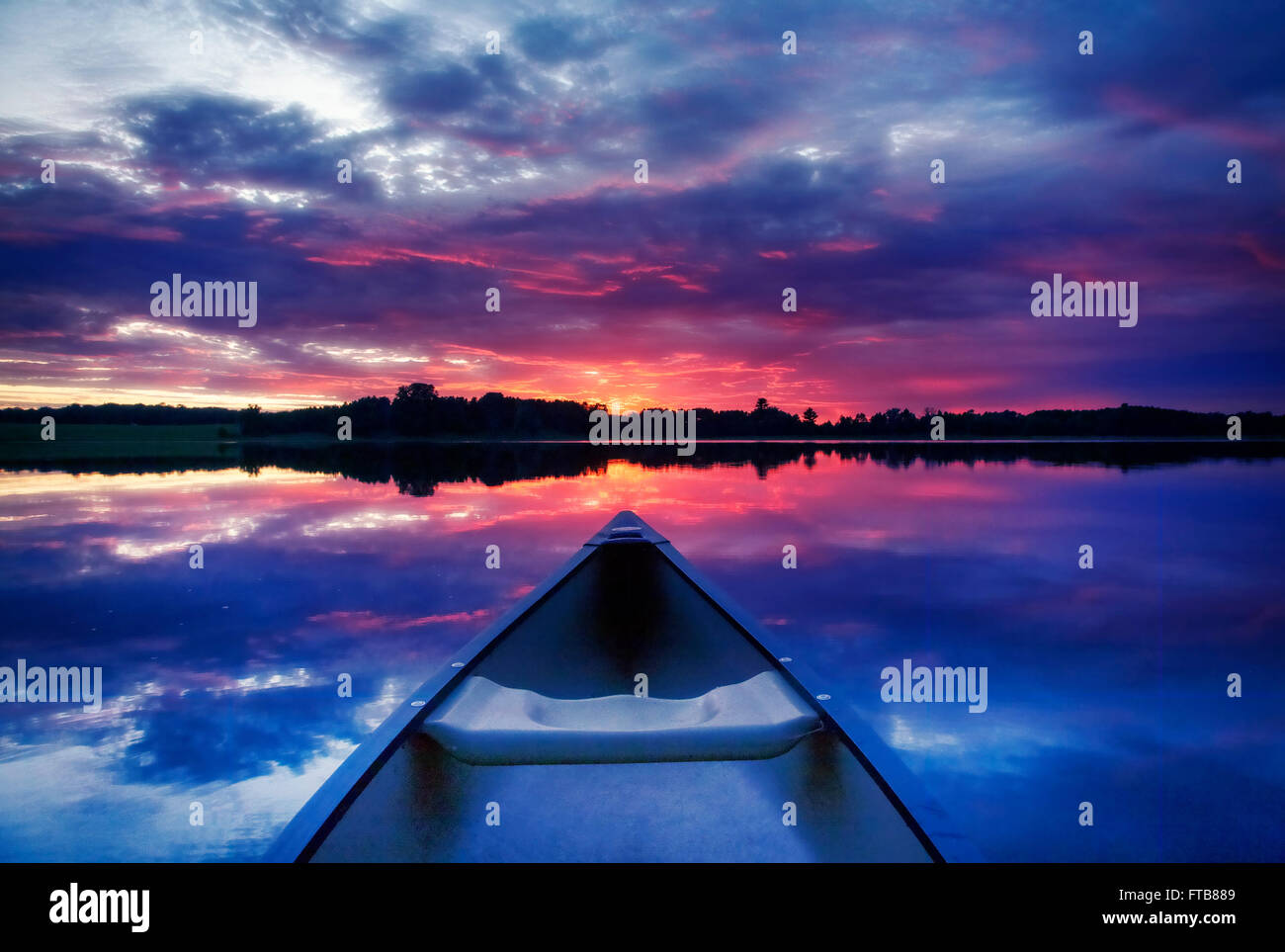 Una canoa punti verso il tramonto su un lago del Minnesota. Foto Stock